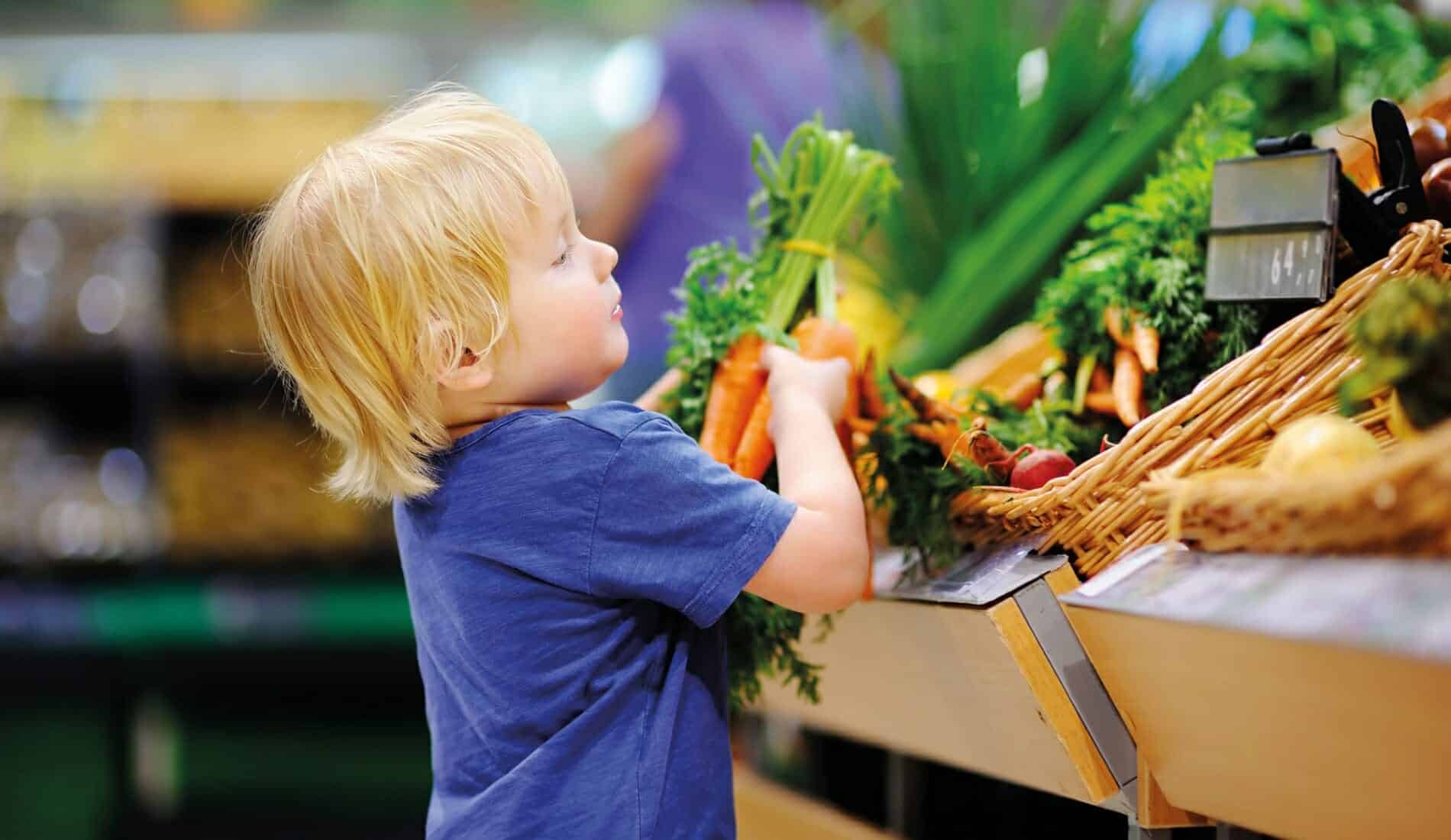 Nachhaltig kochen mit Kindern Kind greift im Supermarkt zu Karotten
