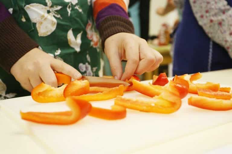 Nachhaltig kochen mit Kindern Kind schneidet roten Paprika