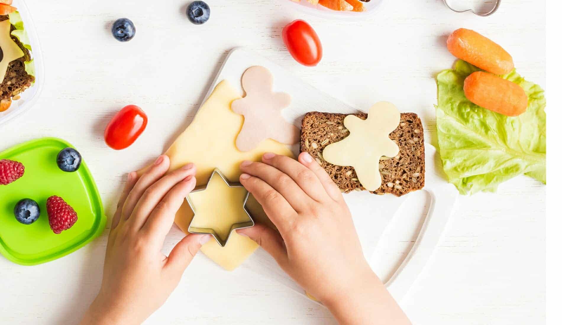 Gesunde Jause Kinderhände stechen Käse für belegtes Brot aus