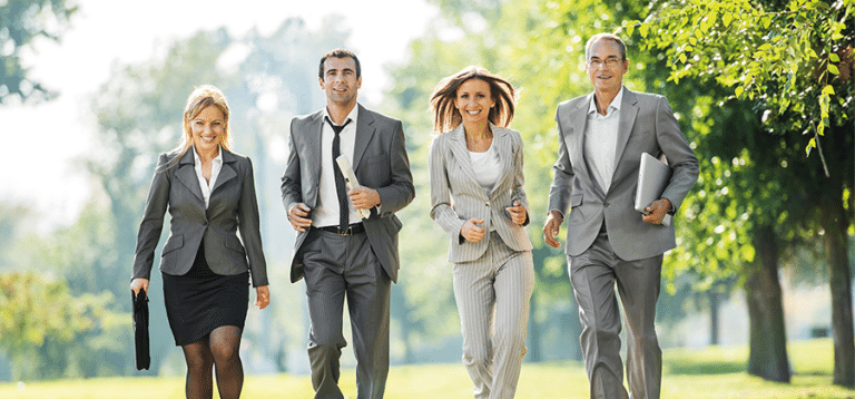 Frauen und Männer im Business-Outfit gehen im Park