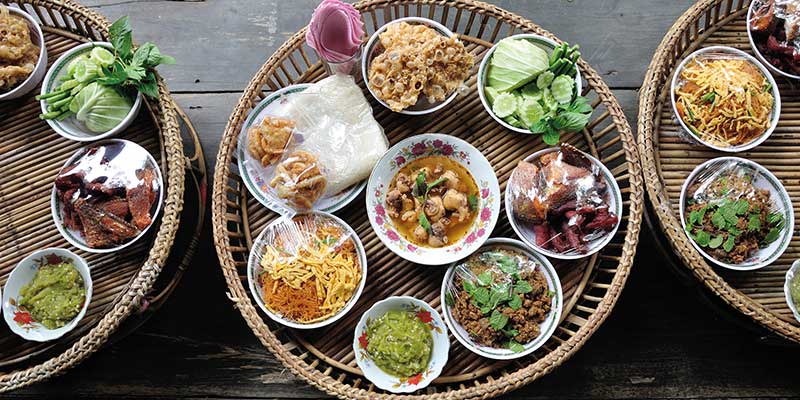 Thailändisches essen in Schüsseln auf Bambustablett